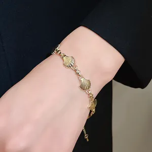 Detail shot of a vintage gold-toned shell-shaped link bracelet worn on a wrist.