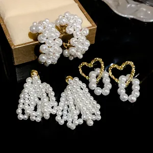 Close-up detail of elegant heart-shaped, tassel and hoop pearl earrings on a dark display