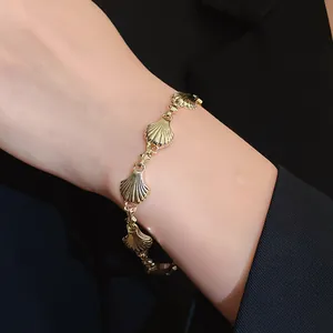 Detailed close-up of a vintage-style gold shell link bracelet on a woman's wrist