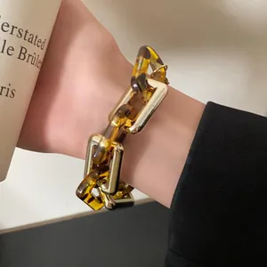 Detailed view of a vintage tortoiseshell and gold metal chunky chain bracelet worn on a wrist