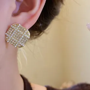 Detailed view of vintage French gold stud earrings with pearls and shiny rhinestones