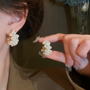 Macro detail view of elegant pearl-encrusted heart-shaped earrings on model ear