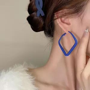 Dettaglio ravvicinato di una modella con orecchini geometrici blu Klein opaco