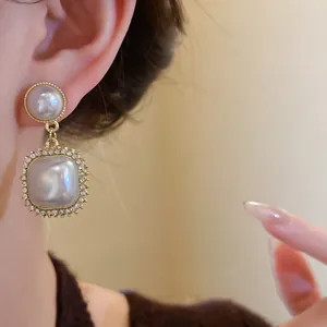 Close-up detail of French vintage gold-toned drop earrings with elegant pearls and rhinestones