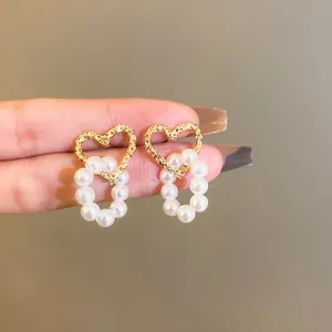 Detailed view of elegant hollow gold heart earrings with dangling white pearl circles