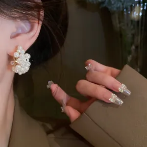 Detailed macro view of elegant white pearl cluster stud earrings worn on a model's ear