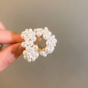 Detailed macro shot of a round gold earring encrusted with white faux pearls, elegant style.