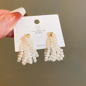 Detailed view of silver needle pearl earrings with hollow heart design and gold beads.