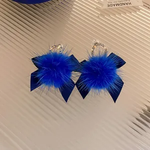 Dettaglio ravvicinato di orecchini pompon blu reale con fiocchi di strass eleganti