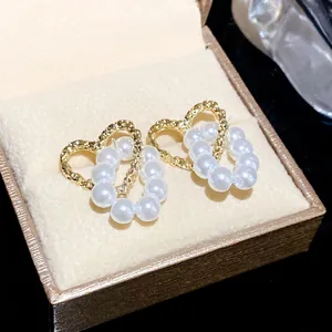 Close-up of elegant hollow heart and pearl earrings in a luxury gift box presentation.