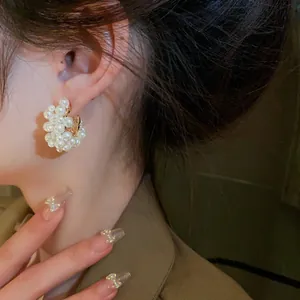 Elegant cluster of white pearls hoop earrings on a model ear with stylish manicure