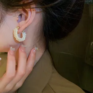 Elegant vintage style woven pearl hoop earrings for women shown on ear close up