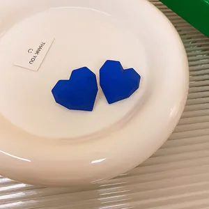 Vista macro dettagliata degli orecchini a lobo a cuore blu Klein sfaccettati geometrici