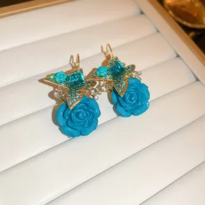 Dettaglio di eleganti orecchini a rosa in resina blu Klein con stelle di cristallo brillanti
