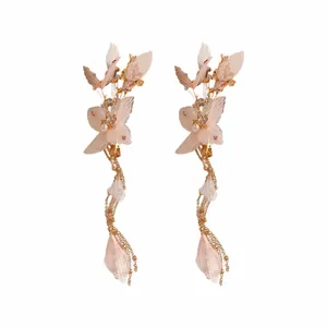 Elegante fermaglio per capelli con fiori di stoffa, perle e nappine su sfondo bianco.