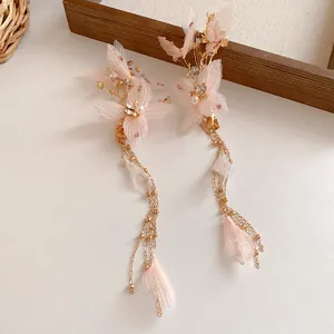 Dettaglio delle mollette per capelli a fiori rosa con catene dorate e perle