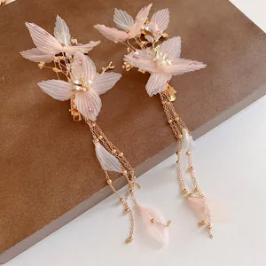 Dettaglio di eleganti fermagli per capelli in tessuto rosa con perle e lunghe nappe