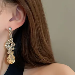 Detail of vintage champagne teardrop earrings with crystals worn by model.