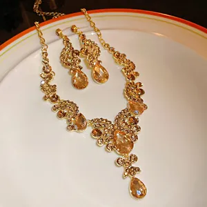 Detailed view of vintage gold necklace and earring set with champagne teardrop crystals.