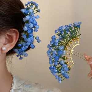 Detailed view of elegant blue baby's breath flower hair fork worn in hair and held in hand