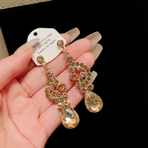 Macro view showing the champagne rhinestones of luxury fan-shaped teardrop earrings