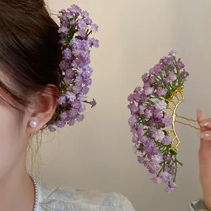 Detail of purple baby's breath flower hairpin on hair and held in hand for hair styling.