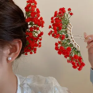 Detail view of red baby's breath floral hairpins worn and held by a model for a forest style look