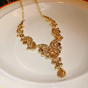 Macro detail of a luxury vintage champagne rhinestone waterdrop necklace on a white plate