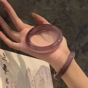 Detailansicht eines eistransparenten lila Harzarmbands am Handgelenk für modernen Look