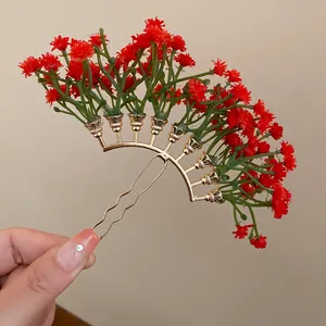 Detailed view of a gold hair fork featuring vibrant red baby's breath floral accents.