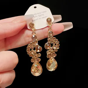 Detailed macro view of champagne crystal teardrop dangle earrings with elegant gold accents