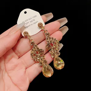 Close-up detail of retro golden teardrop earrings with sparkling rhinestones