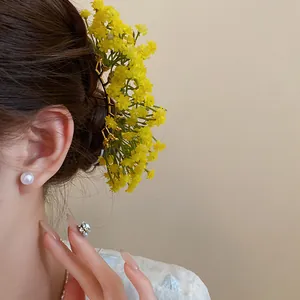Detailed close-up shot of yellow baby's breath flower hair fork worn in person's hair