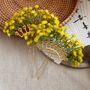 Close-up of yellow gypsophila flower hairpins with golden U-shaped forks on a natural background.