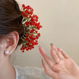 Close-up of red Gypsophila flower hairpin styled beautifully in a feminine hair bun.