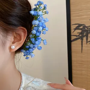 Detail shot of elegant blue gypsophila floral hair pin worn on model with pearls