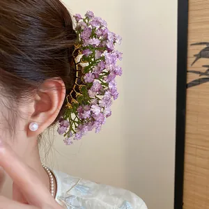 Close-up view of purple gypsophila flower hair fork worn on a model's bun style
