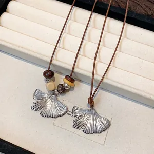 Vintage wood bead necklace with silver ginkgo leaf pendant on a jewelry display box