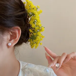 Close-up of yellow baby's breath flower hair pin styled in an elegant forest aesthetic.