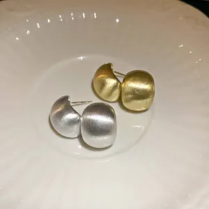 Minimalist brushed metal bean stud earrings in gold and silver with silver needles