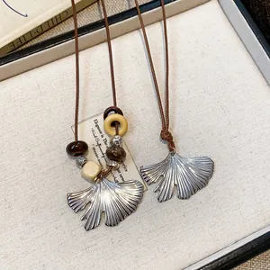 Detailed macro view of ginkgo leaf pendant necklace with elegant handcrafted wood beads