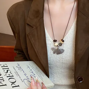 Close-up detail of vintage silver ginkgo leaf pendant necklace with wooden beads