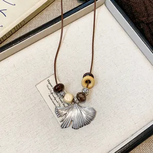 Detailed close-up shot of vintage ginkgo leaf pendant necklace with natural wooden beads