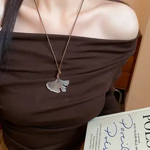 Detailed view of an elegant silver ginkgo leaf pendant necklace with brown woven cord