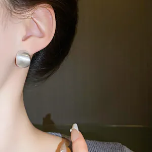Detailed macro view showing the brushed metal texture of minimalist silver bean earrings