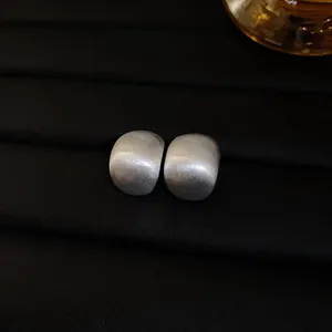 Close-up of brushed silver bean earrings showing detailed matte finish and texture