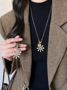Detailed view of gold and silver flower pendant necklaces with tiger eye stones on a model