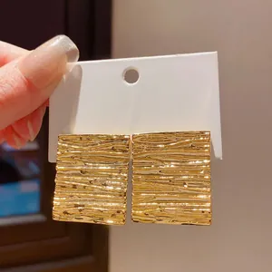 Macro detail shot showing the unique gold textured finish of square stud earrings