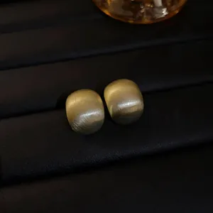 Close-up of matte gold geometric bean stud earrings on black display