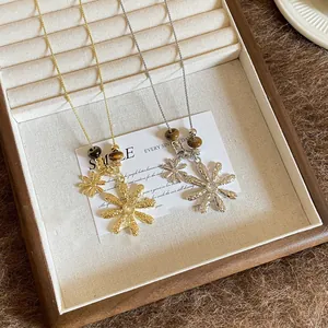Detail view of gold and silver flower necklaces with tiger eye stone beads in a tray